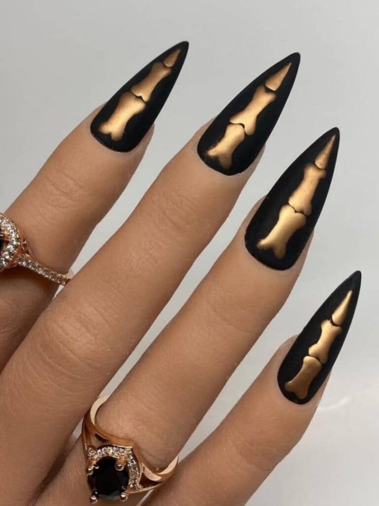 Black stiletto acrylic nails with golden skeleton fingers