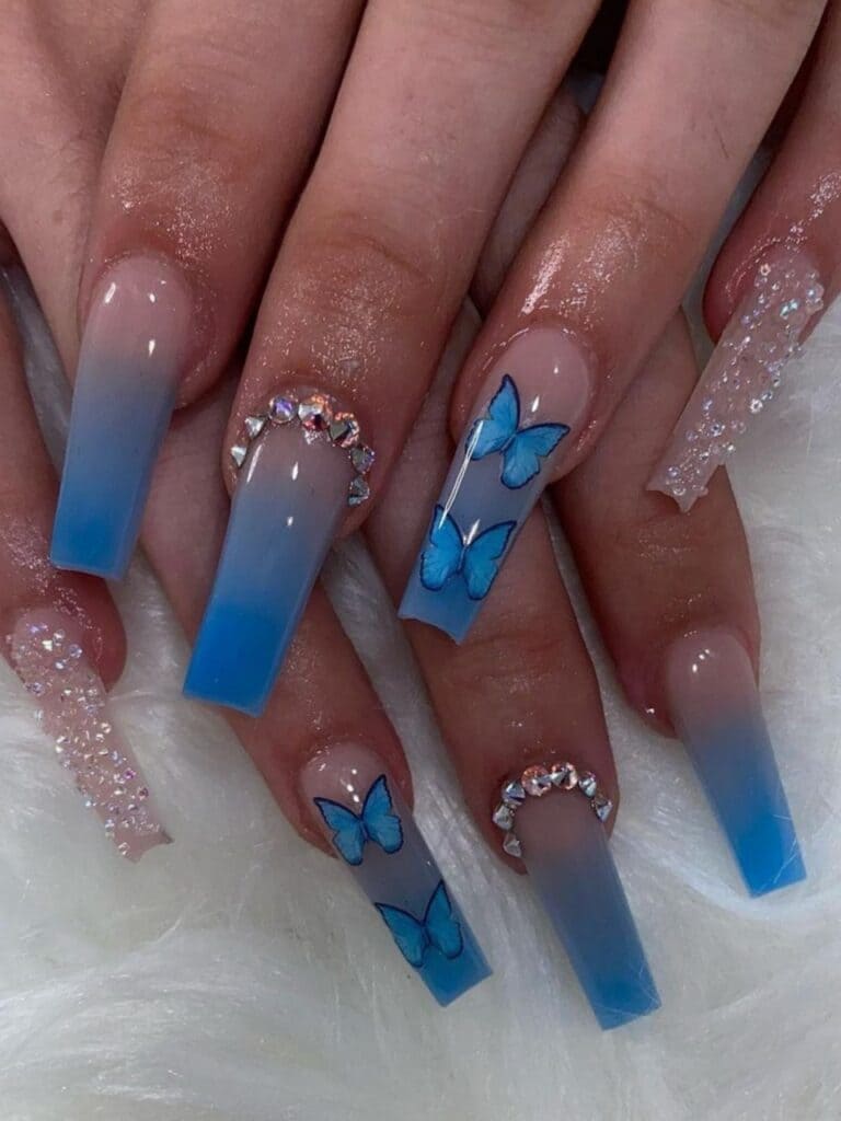Long acrylic blue nails with butterflies and gems