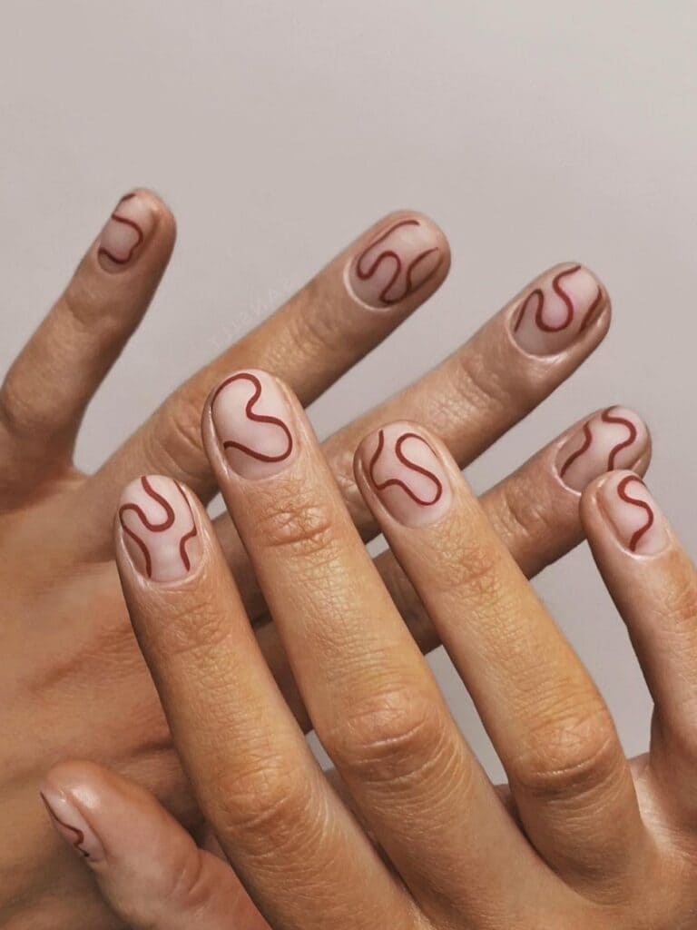 Brown squiggles on short, clear nails