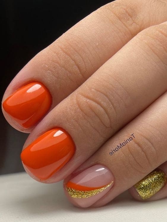 Short orange and gold nails with swirls