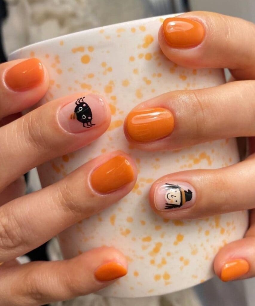 Short orange nails with a cute witch accent 