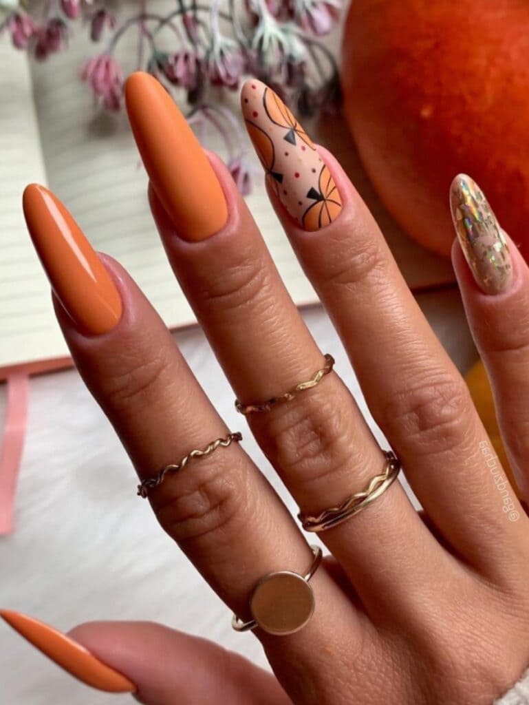 Long, burnt orange nails with pumpkin design