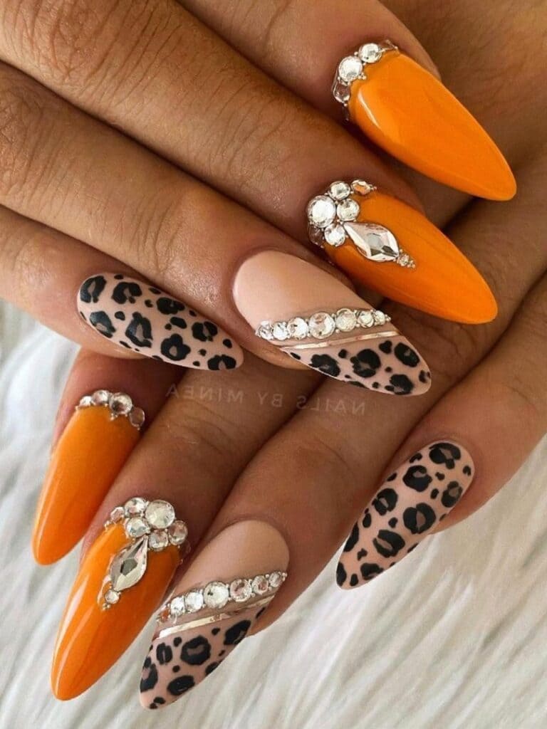 Almond-shaped burnt orange nails with leopard paint and gems