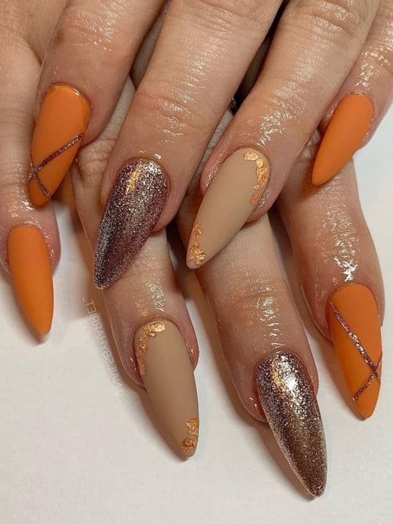 Stiletto-shaped burnt orange, gold, and nude manicure 