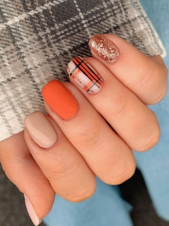 Short orange nails with glitter and plaid