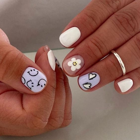 White nails with smiley faces, hearts, and flowers