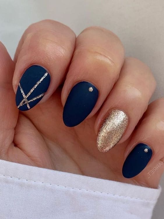 Short, almond-shaped, dark blue and gold nails with geometric lines