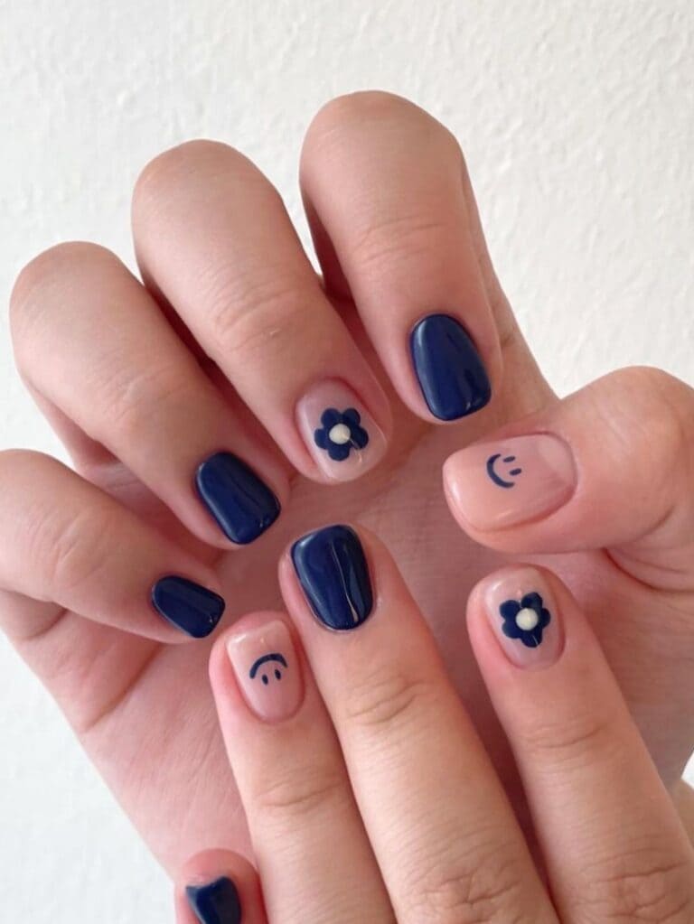 Short, dark blue nails with flowers and smiley faces