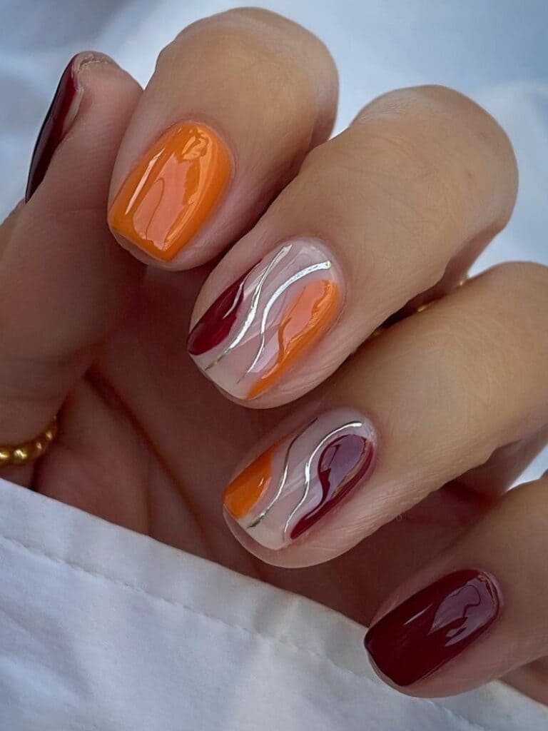 Burnt orange and burgundy fall nails with swirl designs