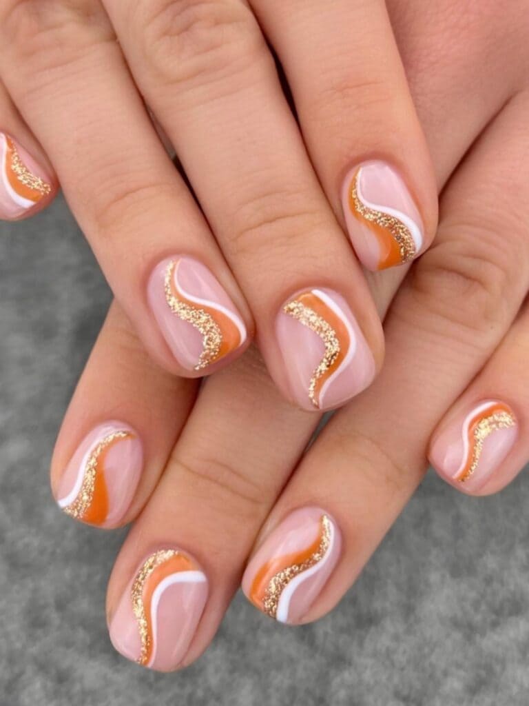 Short, clear nails with burnt orange swirls