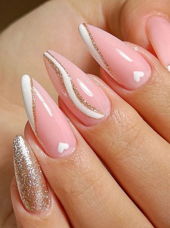 Stiletto-shaped light pink nails with white and gold swirls 