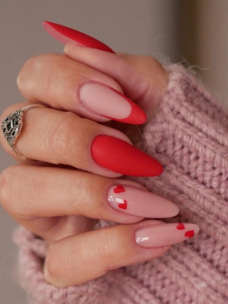 matte red nails with a heart accent