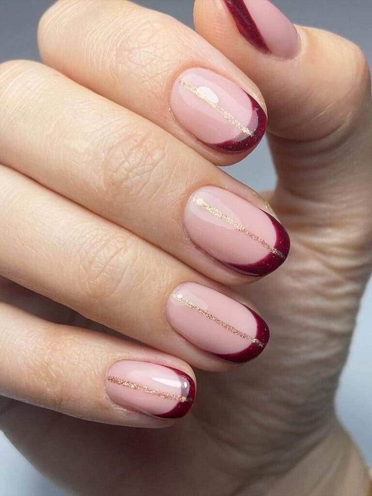 French manicure in burgundy with a gold line accent 