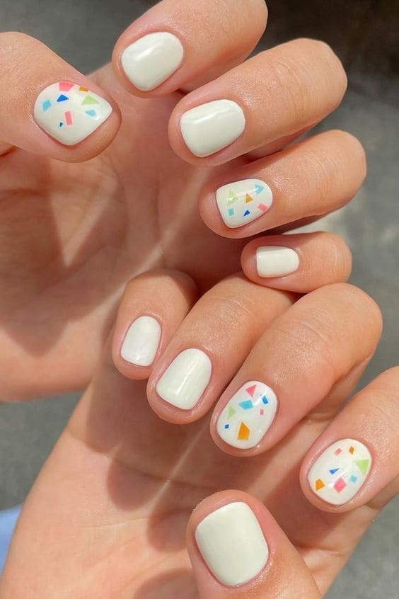 Short white manicure with colorful confetti 