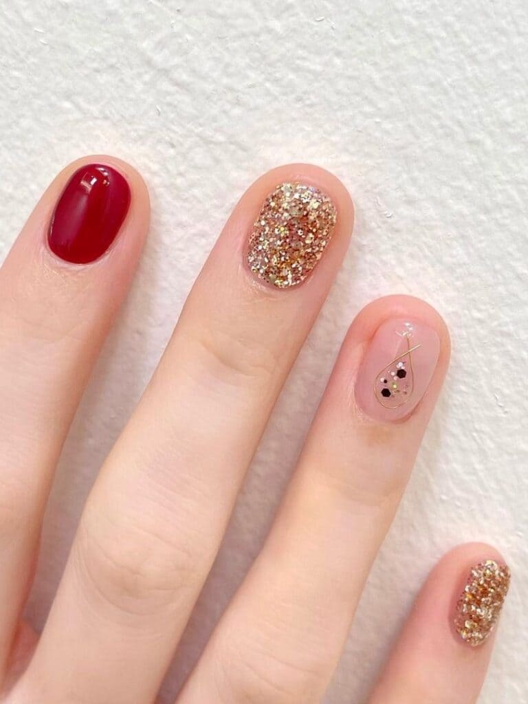 Short, dark red, and gold glitter nails with a simple accent 