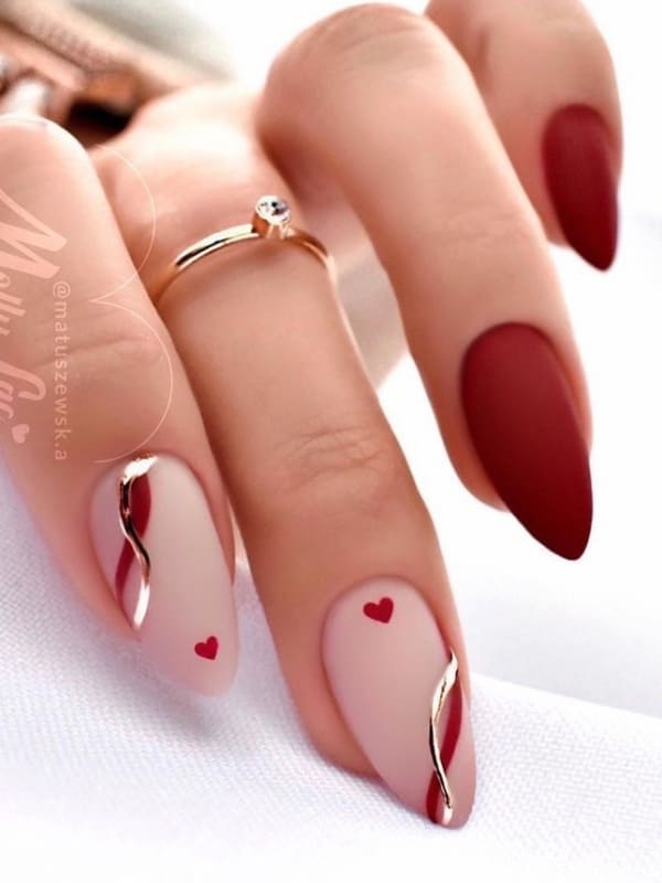almond-shaped, burgundy nails with swirls and tiny hearts