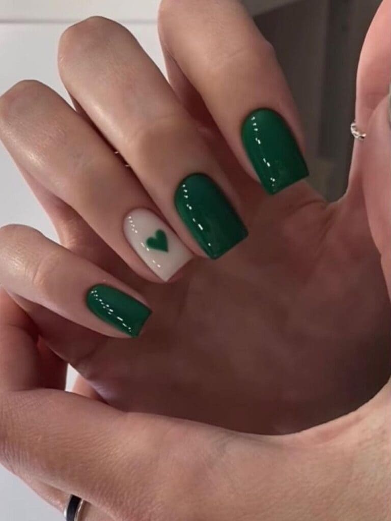 Short, emerald green nails with a heart accent 