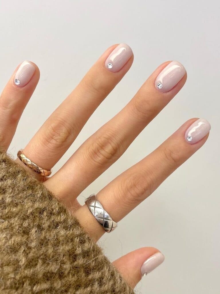 Milky white short nails with a rhinestone accent