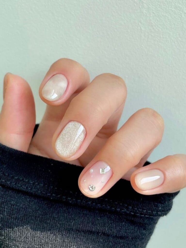 White cat-eye nails with a rhinestone accent