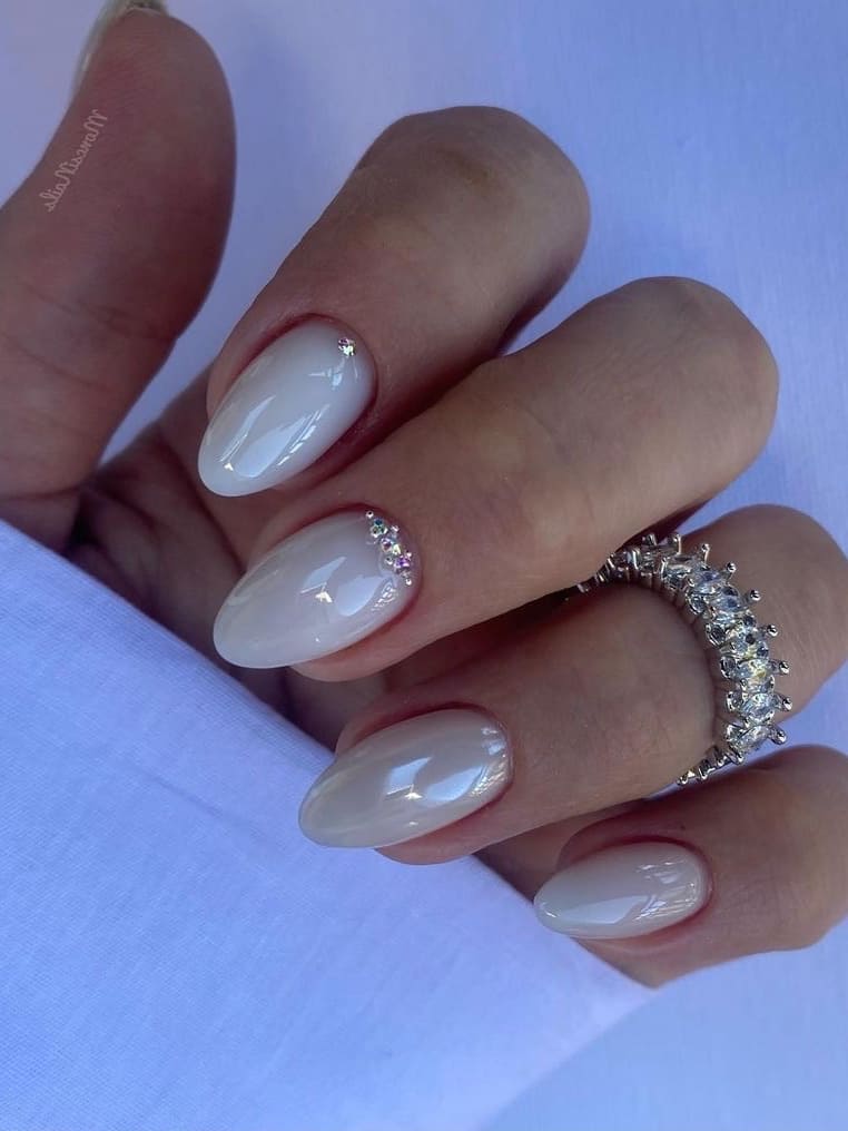 White pearl nails with a rhinestone accent 